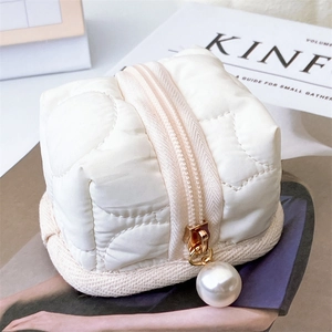 Close-up of white quilted mini pouch with a large decorative pearl zipper pull