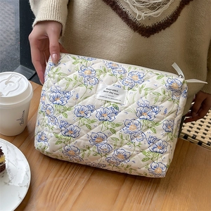 Detailed macro view of blue floral quilted cotton makeup bag with secure zip closure