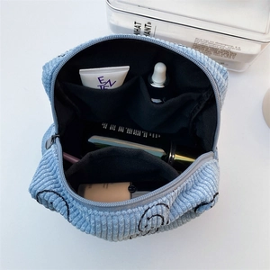 Internal view of blue corduroy makeup bag with multiple compartments and cosmetics
