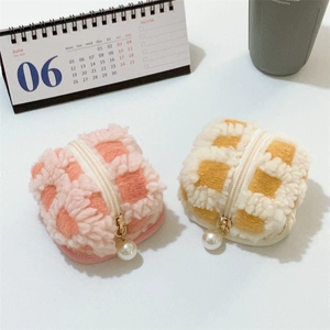 Close-up of plush checkerboard headphone pouches with pearl zipper detail in pink and yellow