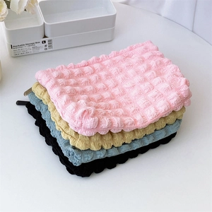 Detailed stack of colorful bubble texture makeup bags in pink, beige, blue and black