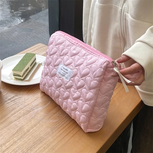 Close-up of pink quilted heart bag with zipper and ribbon on a wooden table