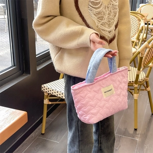 Detailed view of pink quilted tote bag with heart patterns and light blue handles
