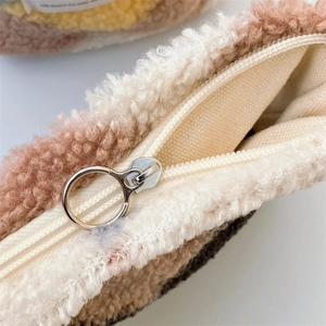 Detail of plush brown striped pouch showing smooth metal ring zipper and canvas lining