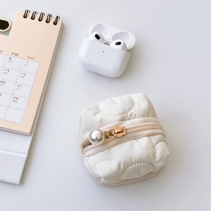 Detailed shot of white quilted earphone pouch featuring a large pearl zipper pull ornament