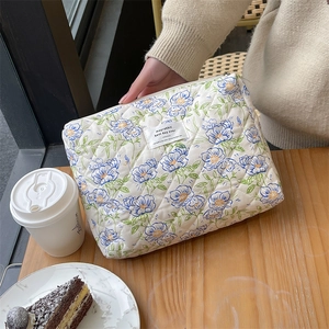 Detailed macro of floral quilted cotton makeup bag with zip on a wooden table setup