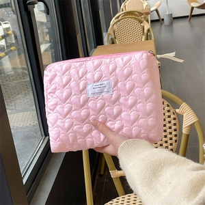 Detail of pink quilted heart pouch showing the soft texture and logo label on the fabric