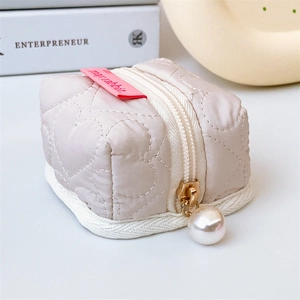 Vue détaillée du petit sac à monnaie beige matelassé en cœur avec pendentif perle