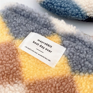 Detail of checkered sherpa fleece fabric texture with brand tag on small square pouch