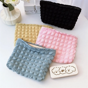 Detailed view of bubble texture fabric makeup bags in assorted pastel colors