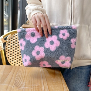 Close-up of plush grey makeup bag with pink flower patterns and zip closure