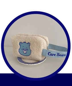 Détail d'une trousse à maquillage en peluche avec broderie Care Bears et poignée bleue