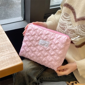 Detail of pink quilted heart makeup bag with soft texture and white woven label