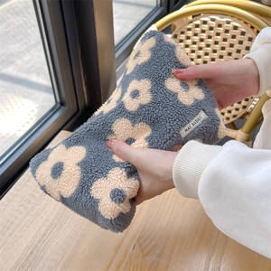 Close-up of soft grey sherpa floral cosmetic bag showing plush texture and brand label