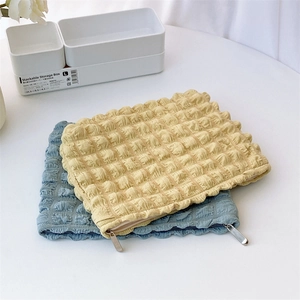 Detailed view of bubble texture on cotton toiletry bags in cream and blue colors
