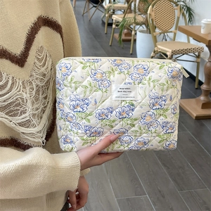Detailed shot of floral quilted cotton makeup bag with metal zipper and logo tag