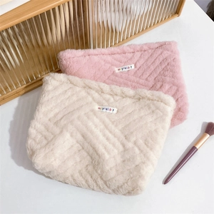 Close-up of plush canvas cosmetic bags with soft geometric texture and brand label