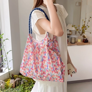 Vista dettagliata della borsa tote floreale con manici in corda blu sulla spalla