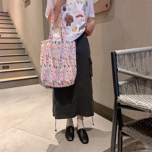 Détail du sac cabas en toile à fleurs roses avec petite étiquette tissée de la marque