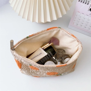 Detail view of large jacquard cosmetic bag with orange floral patterns and metal zipper