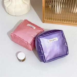 Metallic pink and purple makeup bags with zipper and logo label on a white table