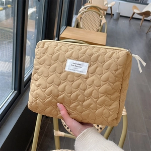 Detailed close-up of quilted heart pattern and label on mustard yellow makeup bag