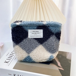 Sherpa quilted cosmetic pouch with blue argyle pattern and zipper closure on a magazine