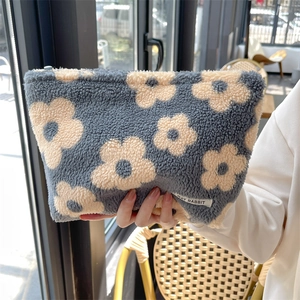 Detail of soft blue floral plush makeup bag showing fabric texture and zipper closure