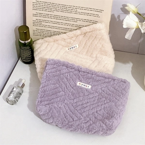 Close-up of plush cosmetic bags with wave texture in purple and beige colors