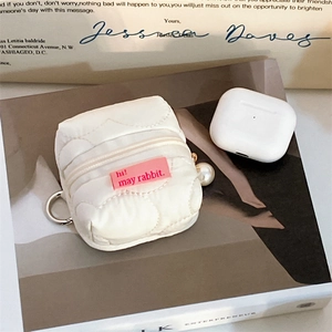 Close-up of white quilted headphone case with pink rabbit label and pearl keychain charm
