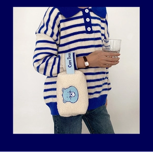Broderie détaillée d'ours bleu sur pochette en peluche blanche avec sangle logo
