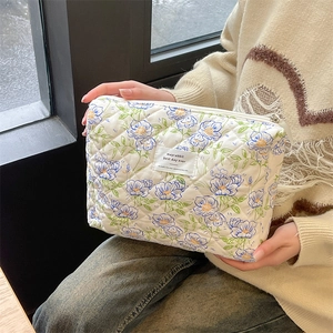 Macro detail of quilted cotton makeup bag with floral prints and brand woven label