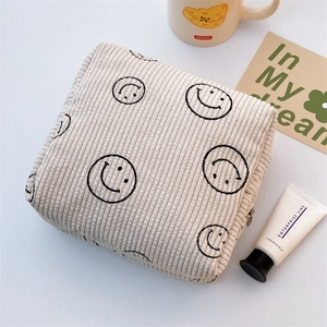 Detail of cream corduroy makeup bag with cute smiley patterns and metal zipper closure