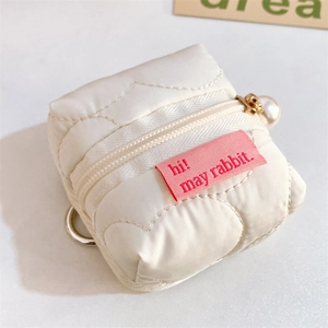 Close-up of white quilted puffer pouch with gold pearl zipper and pink rabbit label