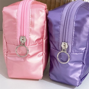 Macro detail of glossy metallic makeup bags with oversized silver ring zippers