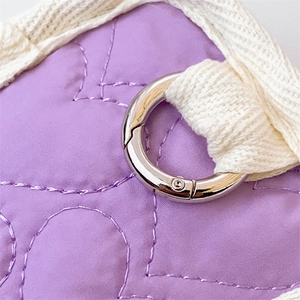 Vue détaillée de l'étui matelassé violet avec anneau argenté et sangle tissée