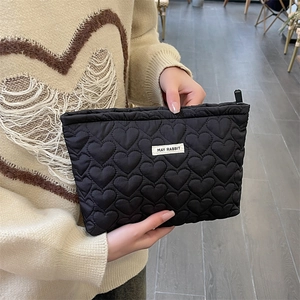 Detail of hand-held black heart-quilted toiletry bag with May Rabbit label
