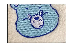 Gros plan détaillé d'une broderie d'hippopotame sur la texture douce d'une trousse à maquillage