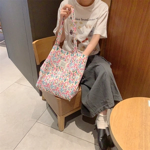 Gros plan sur le sac fourre-tout en toile à fleurs avec motifs bleu et rose au café