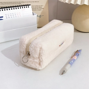 Close-up of white plush pencil case with soft faux fur texture and rainbow letter embroidery