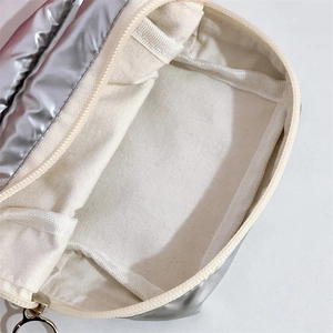 Detail view of the metallic silver cosmetic bag with cream canvas lining and interior pocket