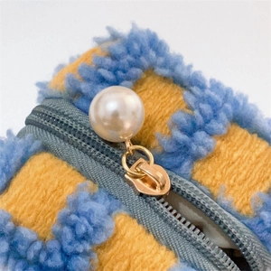 Detail of waffle knit earphone pouch featuring blue-yellow stripes and pearl zipper pull