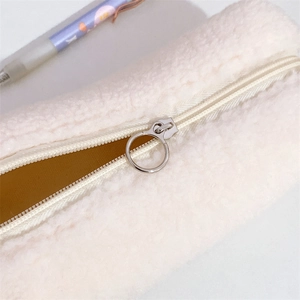 Detail of cream plush pouch with silver ring zipper and mustard yellow interior lining