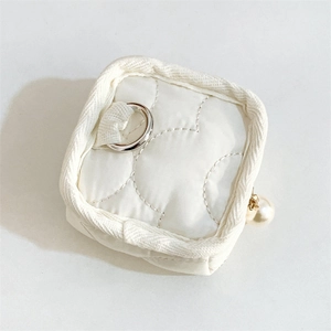 Detail view of a white quilted mini pouch featuring a pearl charm and silver ring hook