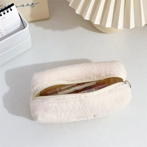 Close-up of plush cream pencil case with metal zipper on a cozy minimalist desk