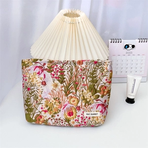 Detailed view of floral jacquard makeup bag with May Rabbit label on a white desk