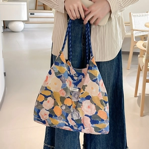 Dettaglio della borsa shopper floreale artistica con manici in corda blu ed etichetta