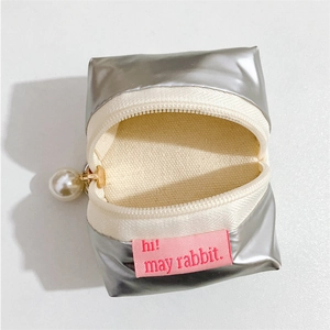 Macro shot of silver metallic headphone case with canvas lining and pearl zipper charm