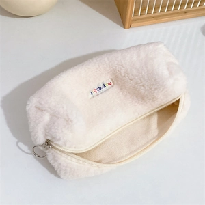 Detail of plush pencil case showing soft white faux fur texture and branded fabric label
