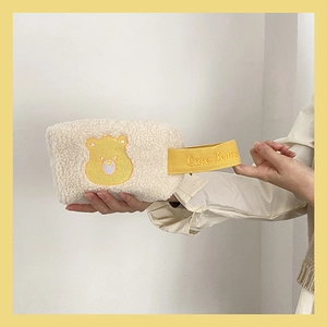 Détail de la trousse à maquillage en peluche blanche avec broderie ours et dragonne jaune